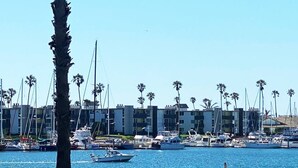 A marina with boats docked, palm trees, and a row of buildings in the background. - Scenic Waterfront Getaway Townhouse with Kayak! (Oxnard)