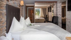 Ein Hotelzimmer mit einem großen Bett, einem Holzkopfende, einer Steinwand und Blick ins Freie.