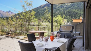 Eine Außenpatio mit Esstisch, Grill und Blick auf Berge.