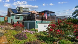 Una casa de dos pisos con balcón, paneles solares y garaje.