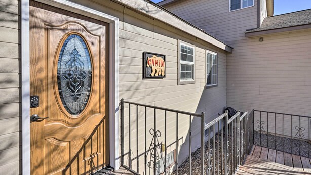 A house with a wooden front door, a 'Cabin' sign, and a small porch with a metal railing. - 'The Cabin' at Grand Valley Getaway w/ Grill! (Grand Junction)