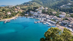 Un pueblo costero con un puerto deportivo, casas y terreno montañoso.