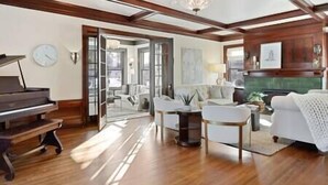 A spacious living room with a grand piano, a fireplace, and a large window allowing natural light. - Luxury 6600 sq.ft Stunning Home/Sleeps 10+ (Minneapolis)