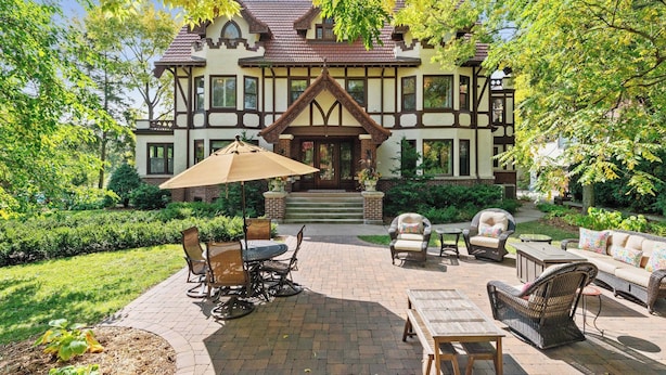 A Tudor-style house with a brick patio, outdoor furniture, and a large umbrella. - Luxury 6600 sq.ft Stunning Home/Sleeps 10+ (Minneapolis)