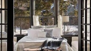 A bedroom with a large window, a bed with white bedding, and a chair. - Luxury 6600 sq.ft Stunning Home/Sleeps 10+ (Minneapolis)
