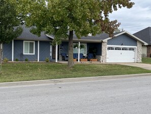 A residential house with a garage, a covered porch with seating, and a lawn. - The Key to your Heart (Nixa)