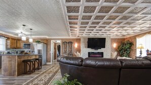 A spacious living room with a leather sofa, a kitchen with a central island, and a fireplace. - The Key to your Heart (Nixa)