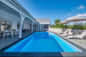 Relax by the pool surrounded by lounge chairs and umbrellas.
