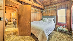 A wooden cabin bedroom with a bed, a small table, and a chair. - Cornell Home w/ Fire Pit & Hunting Access! (Cornell)