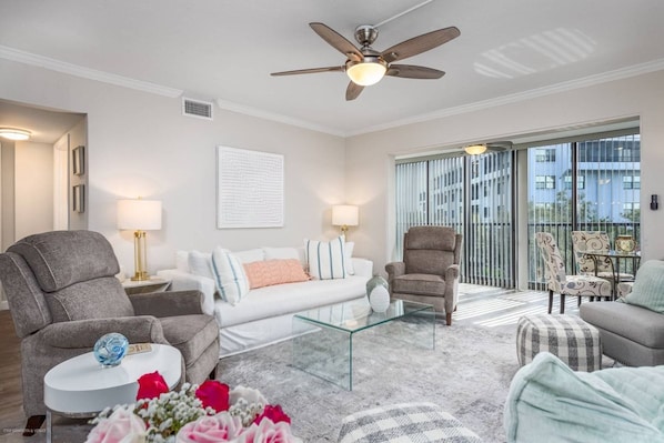 A modern living room with a ceiling fan, a glass coffee table, and a sofa set.