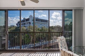 A balcony with a view of a building and trees. - Harbor Towers Corner Suite: Pool & Bay Views (Siesta Key)