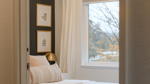 Ein Schlafzimmer mit Bett, Fenster und Lampe.