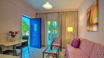 A room with a blue door, a sofa, a chair, a table, and a lamp.