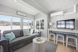 A modern living room with a grey sofa, a round coffee table, and a TV on a white stand. - Vacanza Sleeps 12 with 3 individual units and 3 Docks steps from the Lake (Alton)
