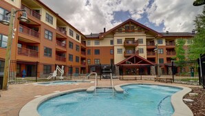 A swimming pool surrounded by a brick patio, with a multi-story building in the background. - Spacious Copper Springs Condo Surrounded by Beautiful Views - CS431 by Redawning (Copper Mountain)