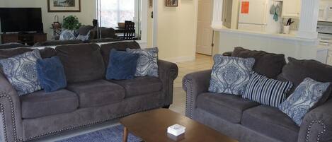 A living room with two grey sofas, a coffee table, and a blue rug.