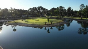 A golf course with a pond reflecting the surrounding trees and buildings. - Golf Course View Brunswick Plantation Condo 1607M by RedAwning (Calabash)