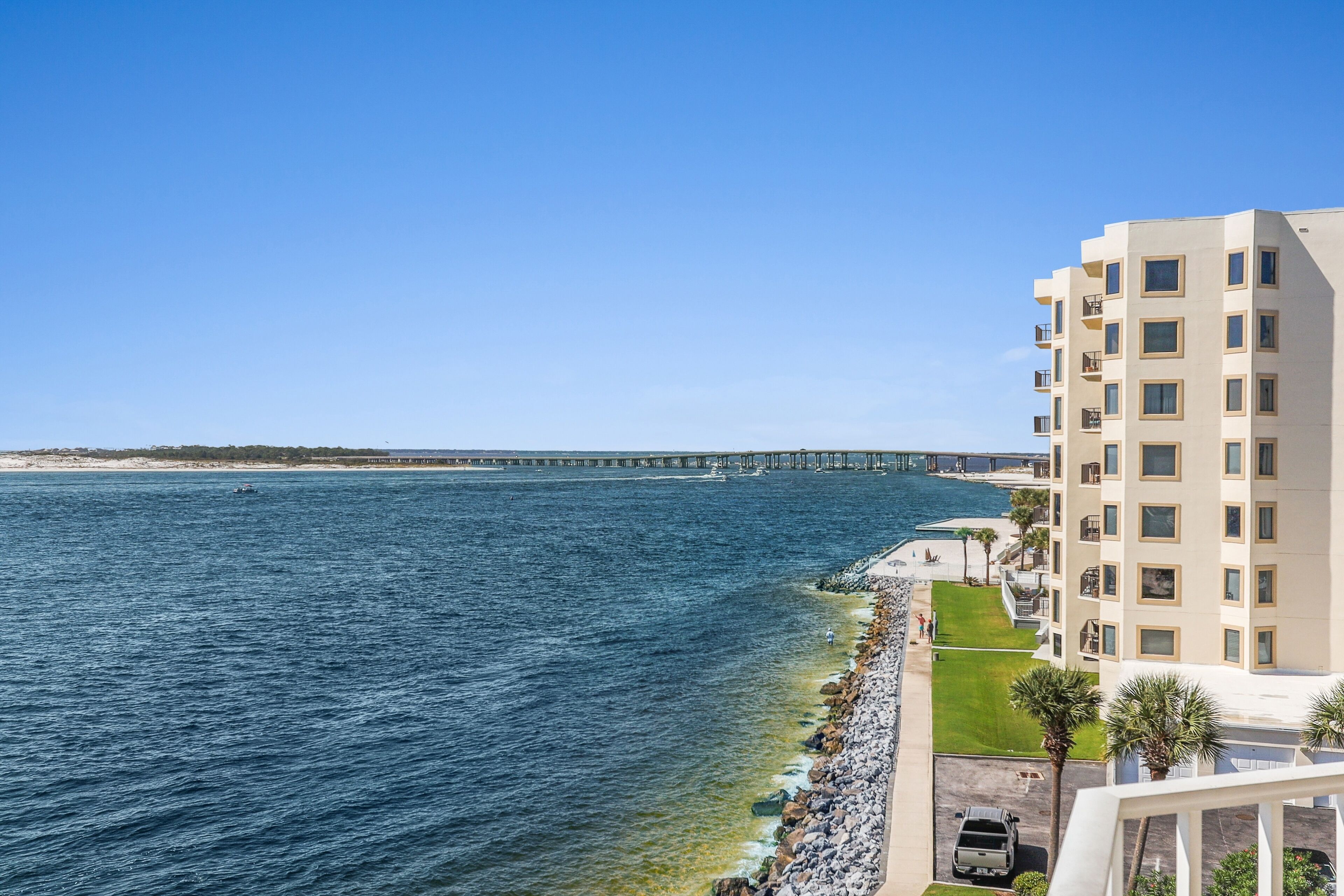 A coastal hotel with a view of the ocean and a pier in the background.