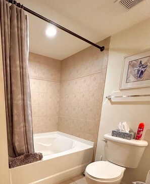 A bathroom with a bathtub, toilet, and a shower curtain.