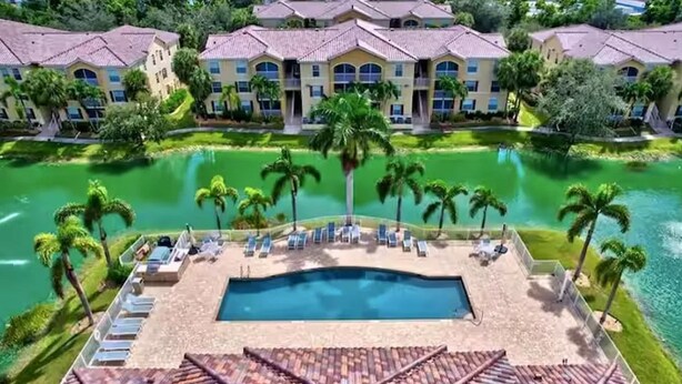 A resort with a swimming pool, lounge chairs, and palm trees. - LOVELY RESIDENCE CONDO TROPICAL RETREAT! (Fort Myers)