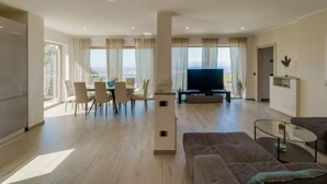 Ampla sala de estar com mesa de jantar, sofá e televisão.