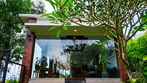 A modern building with a glass facade, a brick exterior, and a small porch area. - Ancala Uluwatu (Pecatu)