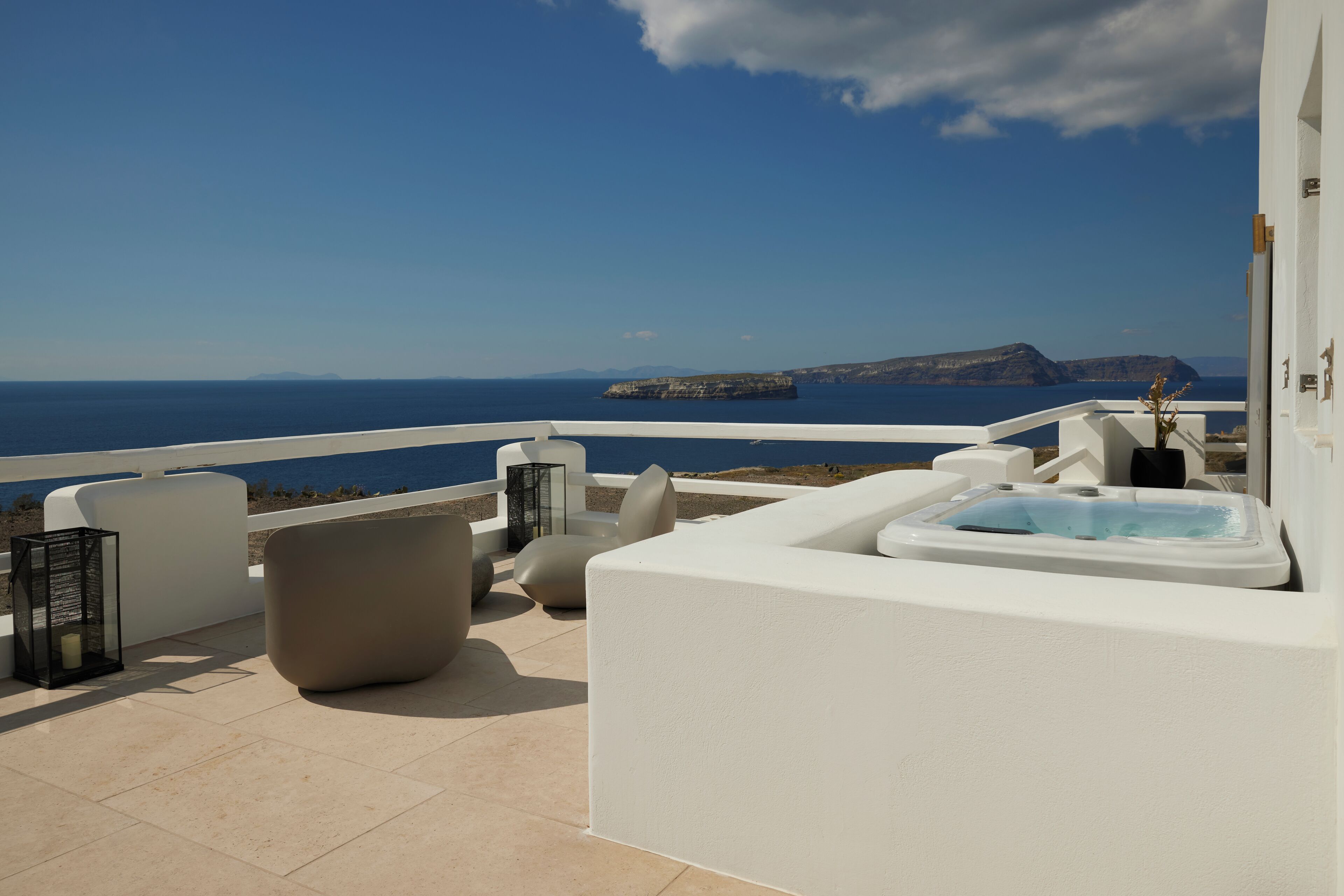 A terrace with a hot tub, seating, and a view of the sea.
