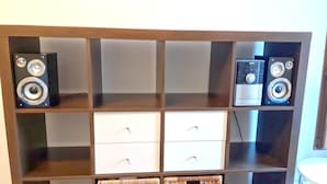 A wooden shelving unit with two large speakers on the top shelf and two white drawers on the bottom shelf. - Apartment with one extra bedroom (Fürstenfeld)