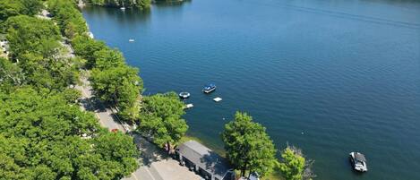 A lakeside property with a dock, boats, and a road leading to a building.