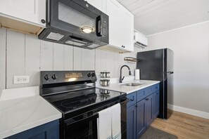 A modern kitchen with a black stove, white cabinets, and a black refrigerator.