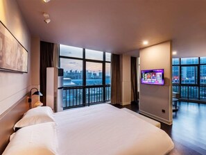 Habitación de hotel con una cama grande, televisión de pantalla plana, vista a la ciudad y cortinas.