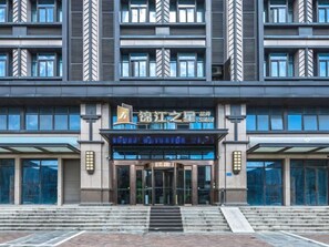 Un bâtiment moderne doté d’une entrée imposante, de grandes fenêtres et d’une enseigne indiquant qu’il s’agit d’un hôtel ou d’un établissement proposant des hébergements.