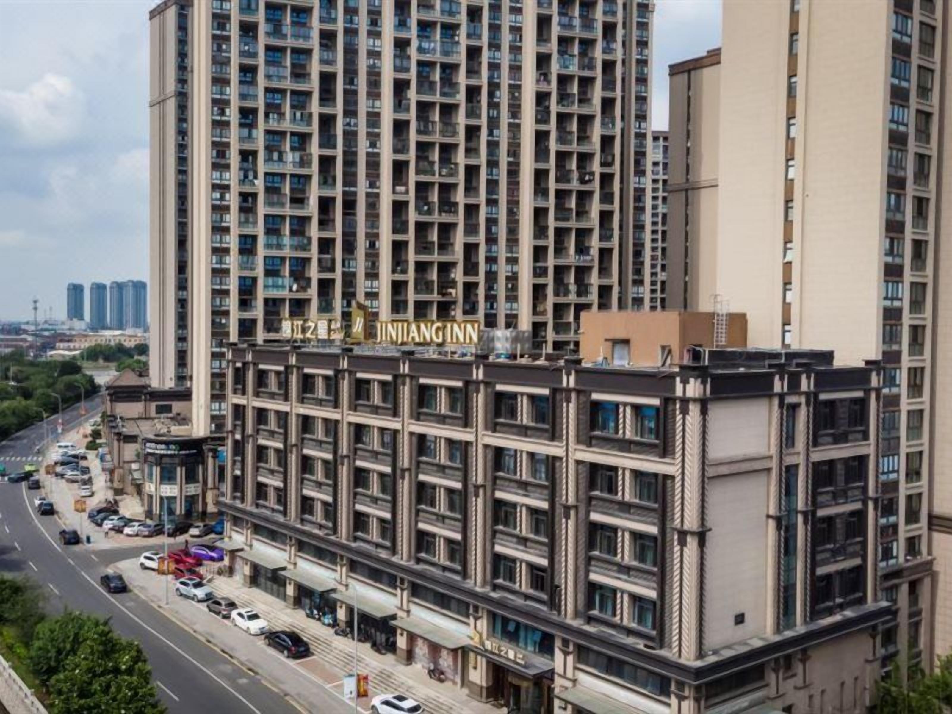 Un hotel de varios pisos con una señalización llamativa, una calle al frente y otros edificios en el fondo.