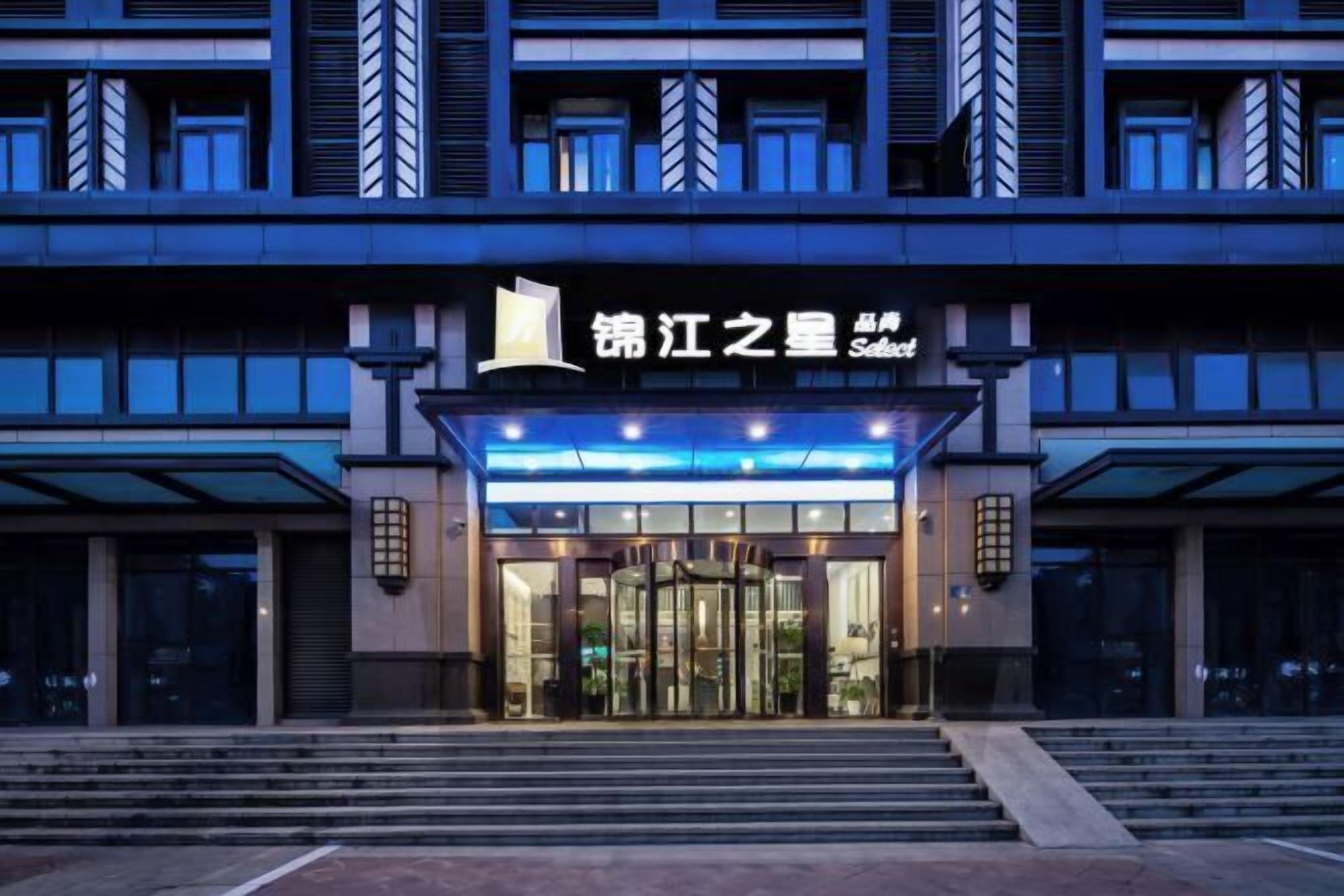 Una entrada de hotel moderna con puerta giratoria, escalones que conducen a la entrada y un letrero sobre la puerta.