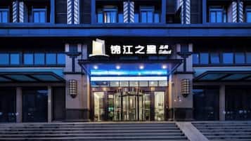 Una entrada de hotel moderna con puerta giratoria, escalones que conducen a la entrada y un letrero sobre la puerta.