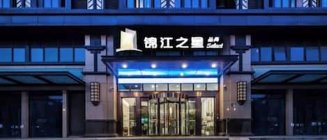 A modern hotel entrance with a revolving door, steps leading up to the entrance, and a sign above the door.
