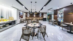 A modern restaurant with a central dining area, multiple tables and chairs, pendant lighting, and a bar area with shelves.