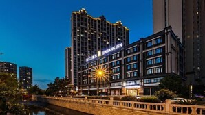 A high-rise hotel with a prominent 'INGIN' sign, surrounded by other buildings and a canal.