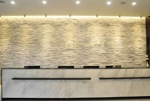 Un mostrador de recepción con una pared con textura y un logotipo.