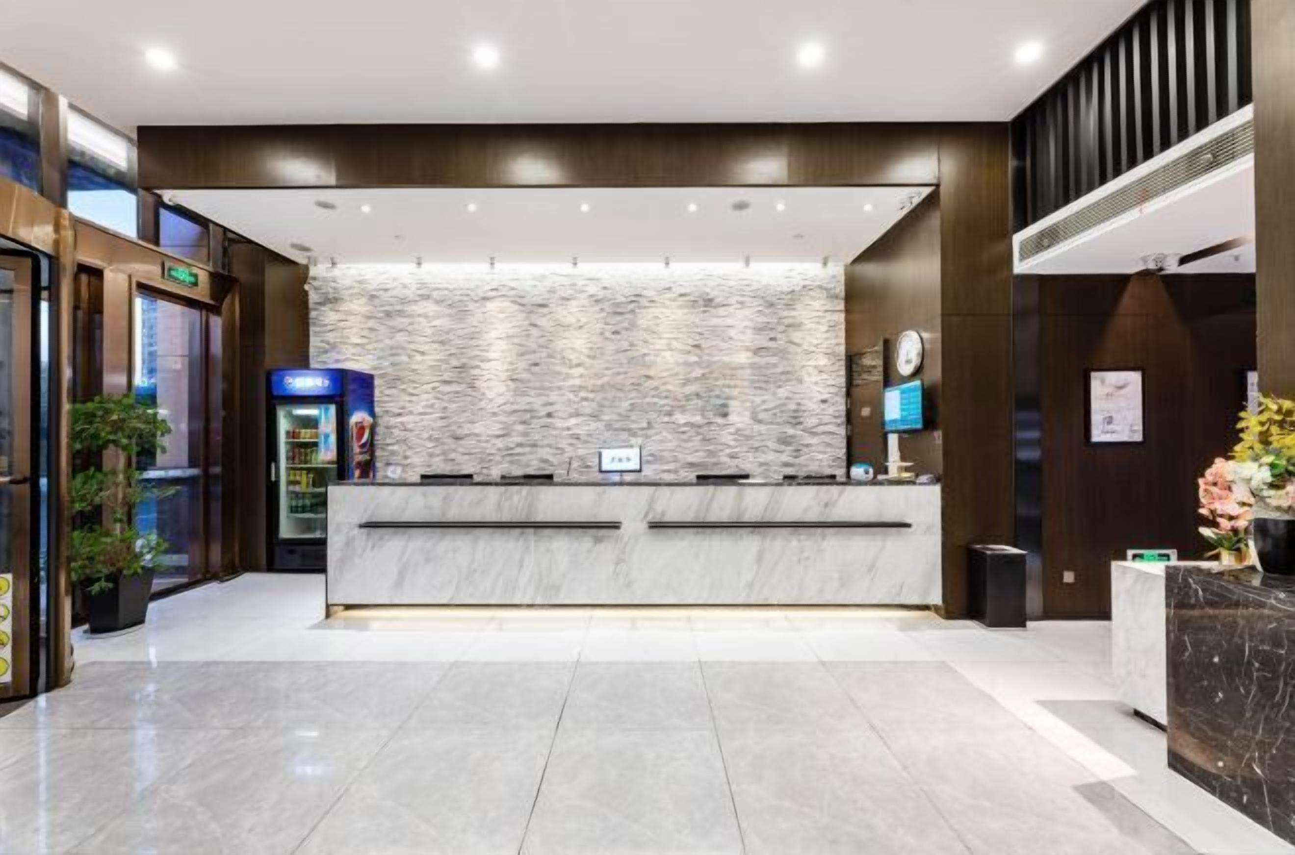 A modern reception area with a marble counter, a stone wall backdrop, and a clock on the wall.