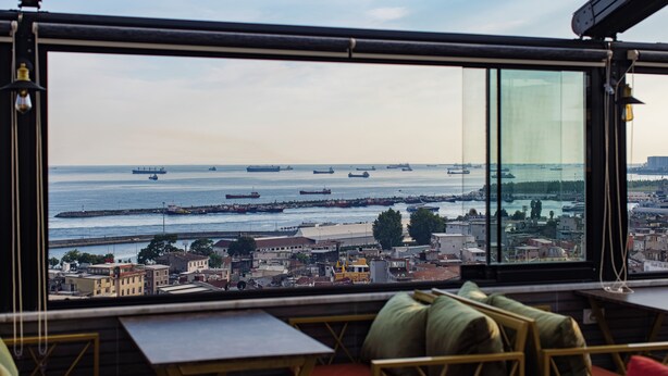 A view from a high-rise building overlooking a harbor with multiple ships, a cityscape, and a clear sky. - Grand Balyan Hotel & Restaurant (Istanbul)