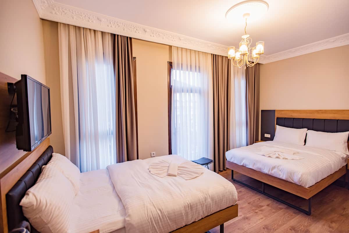 A hotel room with two beds, a TV, and a chandelier.