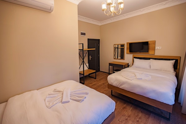Habitación de hotel con dos camas, televisión, espejo y candelabro.