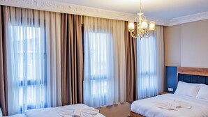 A hotel room with two beds, wooden flooring, a chandelier, and large windows with curtains. - Grand Balyan Hotel & Restaurant (Istanbul)