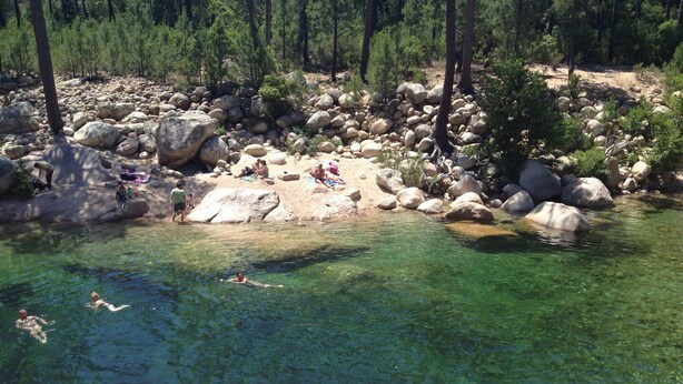 Un'area piscina all'aperto ben definita, circondata da grandi rocce e alberi.