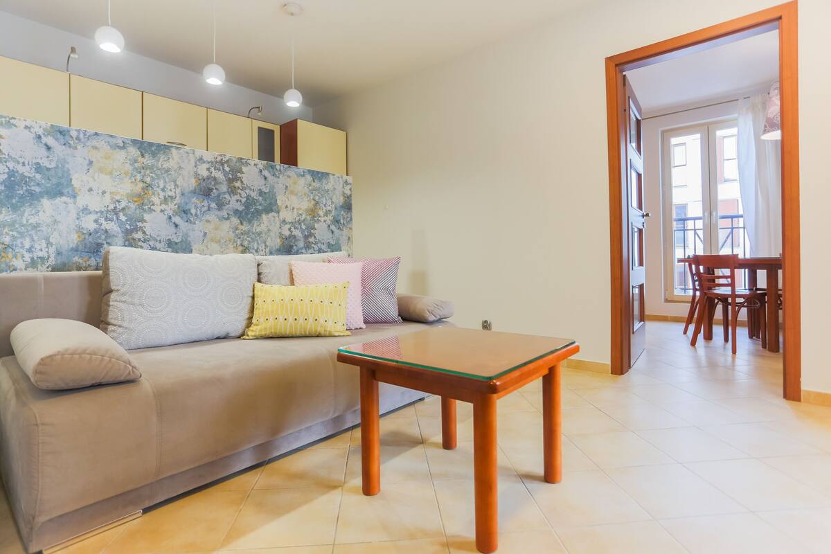 A living room with a sofa, a wooden coffee table, and a dining area with chairs and a table.