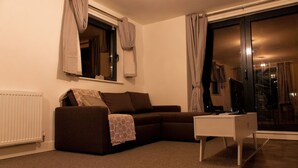 Ein Wohnzimmer mit einem braunen Sofa, einem weißen Couchtisch und einem Fenster mit Vorhängen.