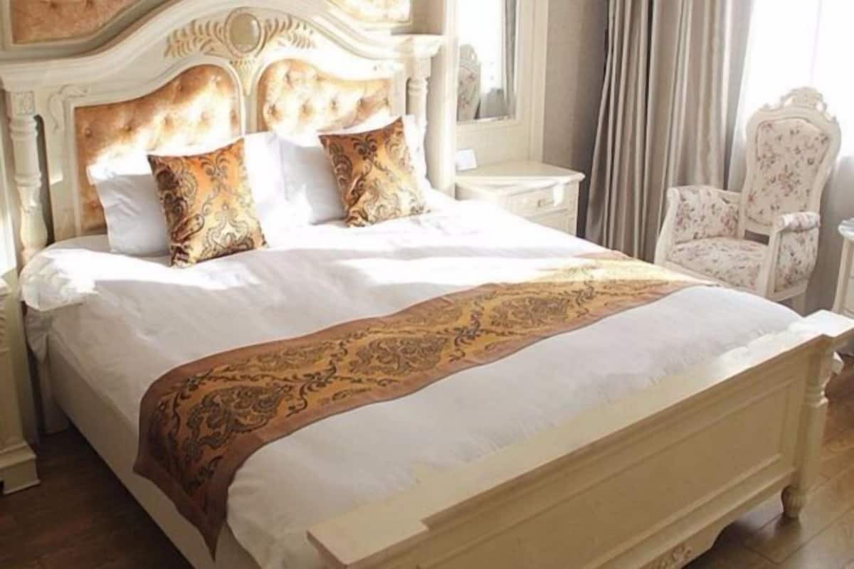 A bed with a headboard, two pillows, and a decorative throw.