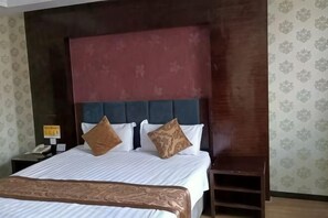 A hotel room with a large bed, a wooden headboard, a nightstand with a phone, and patterned wallpaper. - Beiyuan Hotel (Sunwu)