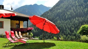 Ein Haus mit einem roten Regenschirm, einem Holzzaun und einem Berg im Hintergrund.